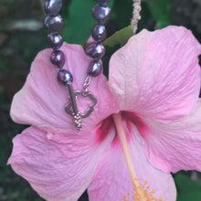 Load image into Gallery viewer, Knotted pearl bracelet hanged  on top of pink hibiscus