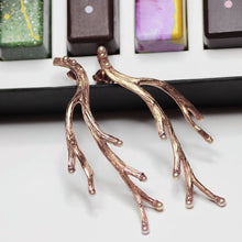 Load image into Gallery viewer, Rose gold long earrings placed on a box of fancy colored chocolates