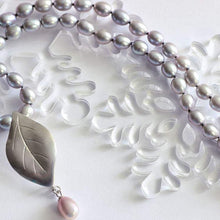 Load image into Gallery viewer, Global view of grey pearls knot necklace, leaf silver pendant necklace, place on a snow flakes decoration