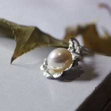 Load image into Gallery viewer, Silver flower pendant, white pearl, white background, dried leave in the back