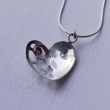 Load image into Gallery viewer, Sterling silver heart pendant with a red garnet cabochon, face down on white background