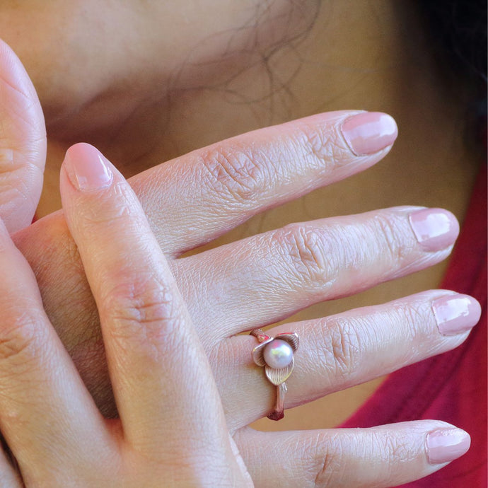 Woman wearing rose gold flower ring crossed hand and red top