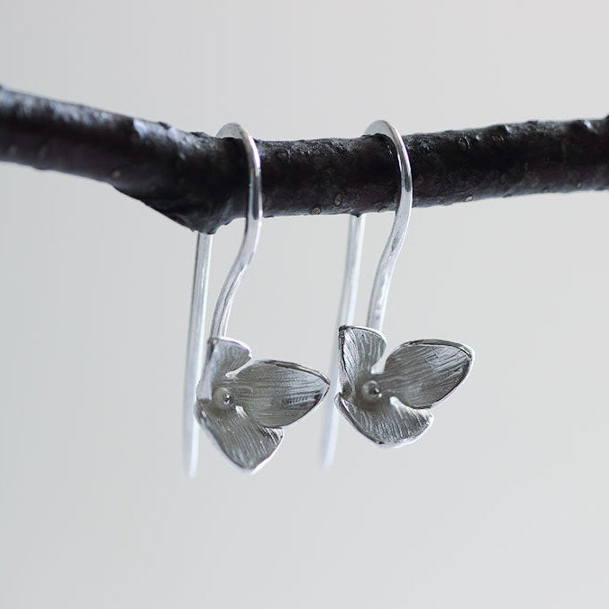 Trillium silver drop earrings for every day hanged on black branch - white background