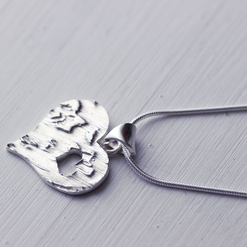 <tc>Grand pendentif cœur texturé avec un petit cœur découpé</tc>