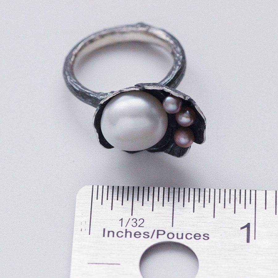 Cocktail ring, black silver, flower and twig designs on white background, top placed near a ruler for dimension