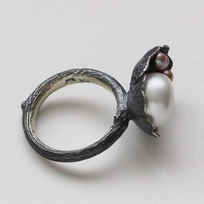 Cocktail ring, black silver, flower and twig designs, side view, placed on a white background