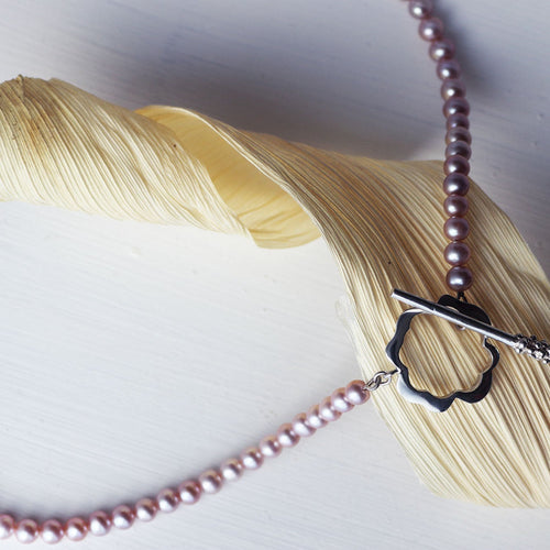 Flower necklace, pink pearls displayed on a dryed corn leave